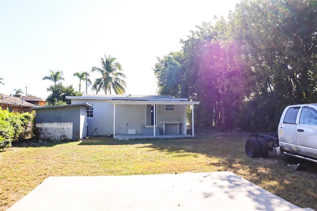 view of front of property featuring stucco siding, solar panels, and a front lawn