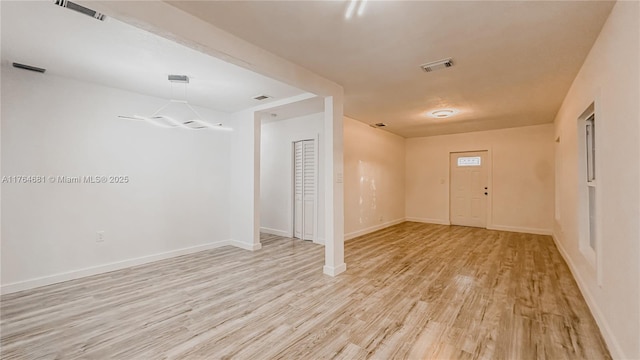 empty room featuring light wood-type flooring, visible vents, and baseboards