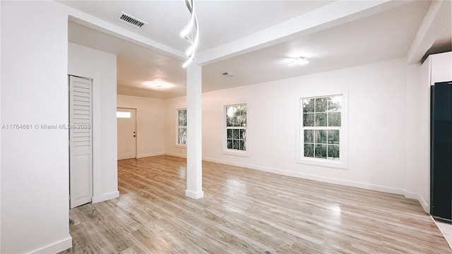 empty room featuring visible vents, baseboards, and light wood finished floors