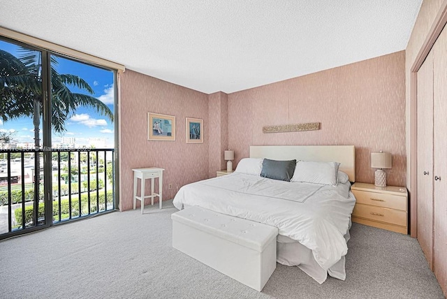 carpeted bedroom with wallpapered walls, a closet, and a textured ceiling