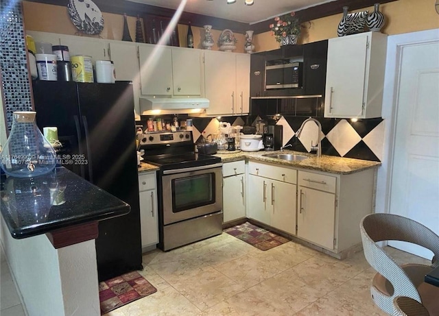 kitchen with light stone countertops, freestanding refrigerator, a sink, stainless steel range with electric cooktop, and under cabinet range hood