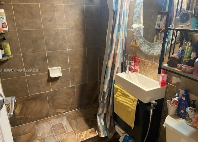 bathroom with a sink, tile walls, toilet, and tiled shower