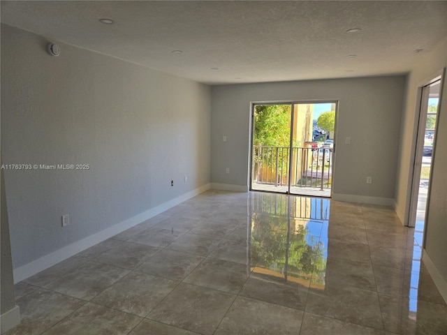 empty room featuring a textured ceiling and baseboards