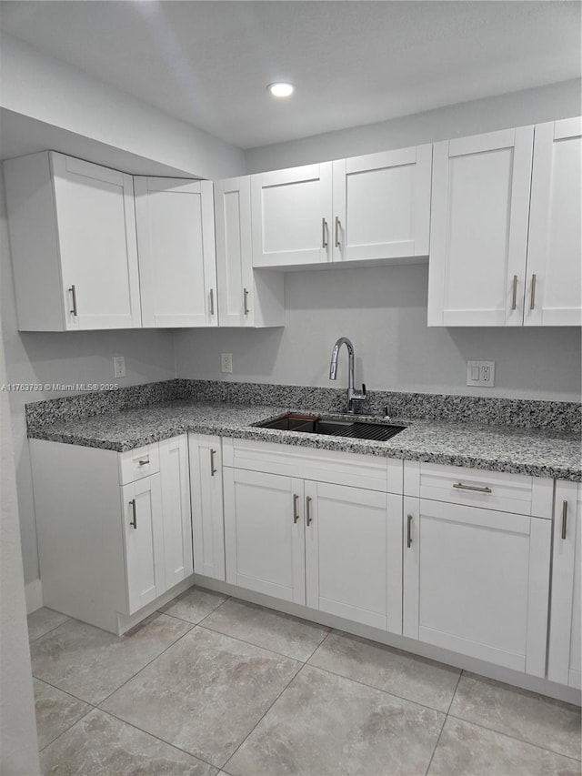 kitchen with white cabinets, recessed lighting, stone counters, and a sink