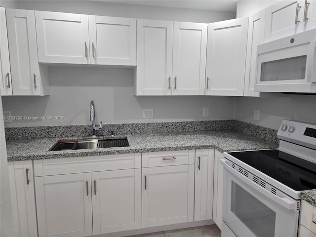 kitchen with white cabinets, white appliances, light stone countertops, and a sink