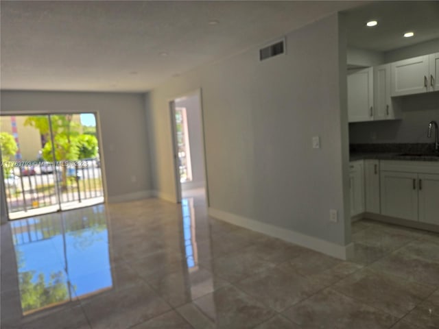 unfurnished living room with a sink, visible vents, baseboards, and recessed lighting