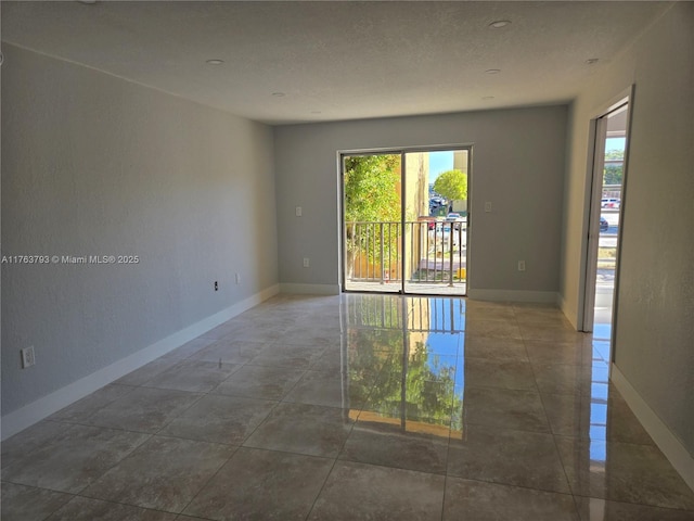 spare room featuring tile patterned floors and baseboards