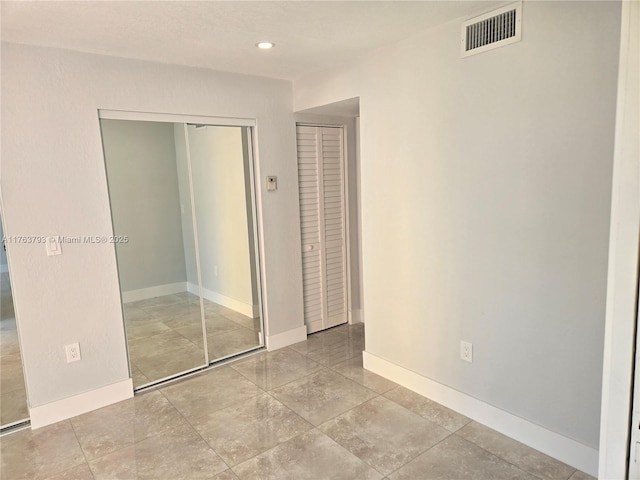 unfurnished bedroom with a closet, visible vents, recessed lighting, and baseboards