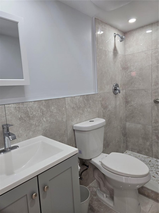 full bath featuring vanity, tile walls, toilet, and a tile shower