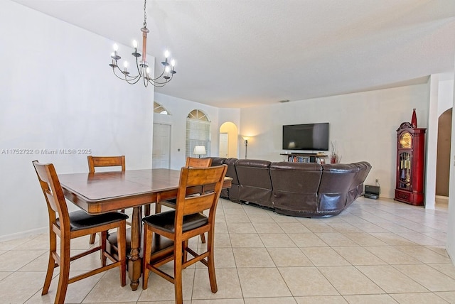 dining area with a notable chandelier, baseboards, arched walkways, and light tile patterned floors