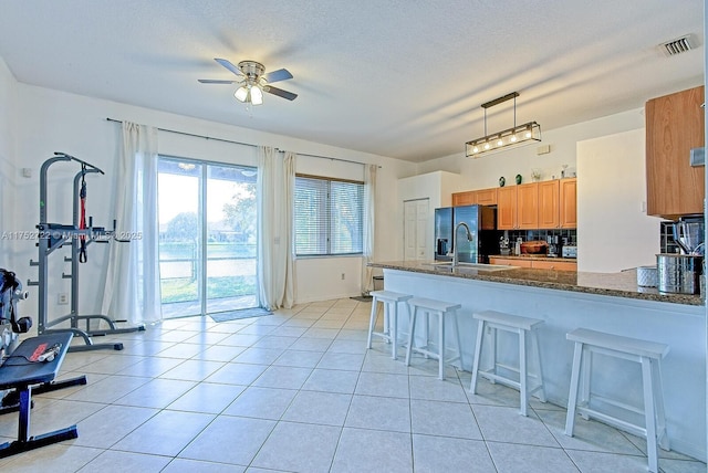 kitchen with visible vents, a ceiling fan, a kitchen breakfast bar, light tile patterned floors, and black refrigerator with ice dispenser