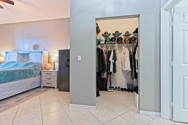 bedroom featuring a walk in closet, light tile patterned floors, baseboards, and a closet