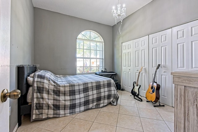 bedroom with a notable chandelier, light tile patterned flooring, and a closet