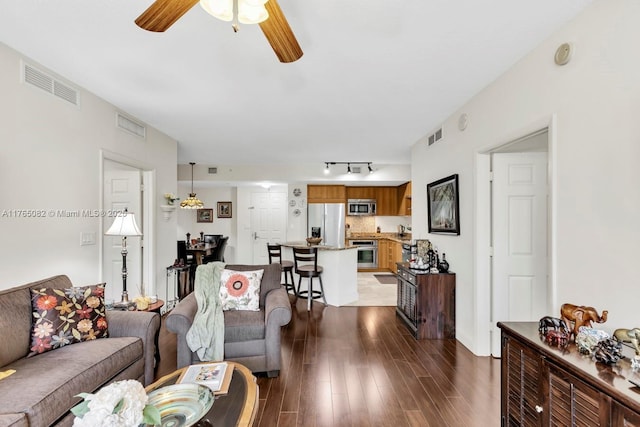 living room featuring dark wood-style floors, visible vents, and a ceiling fan