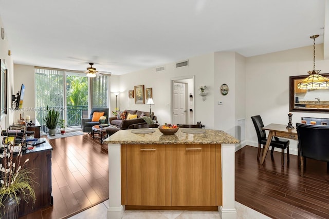 kitchen with visible vents, decorative light fixtures, a wall of windows, light wood-style floors, and a ceiling fan