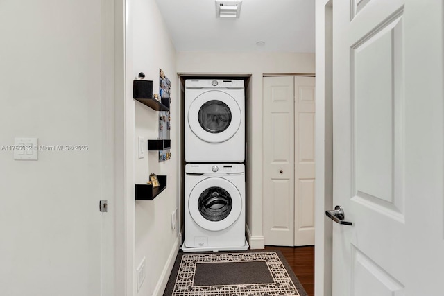 clothes washing area with visible vents, stacked washer and dryer, wood finished floors, and laundry area