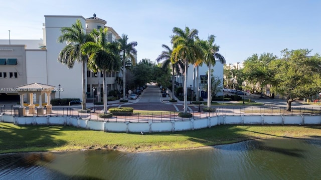 view of community featuring a lawn, fence, and a water view