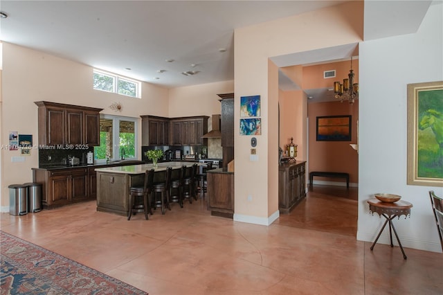 12301 SW 107th Ave, Miami, FL 33176 - kitchen with wall chimney exhaust hood, dark brown cabinets, a breakfast bar area, a center island, and a chandelier
