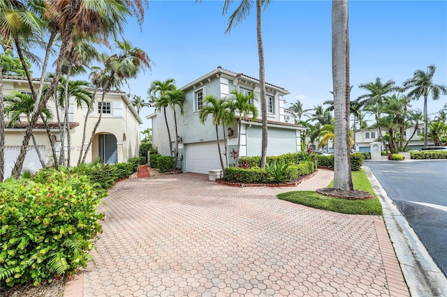 view of front of house with stucco siding, decorative driveway, and a garage