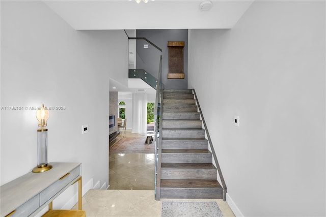 stairway featuring a high ceiling and baseboards