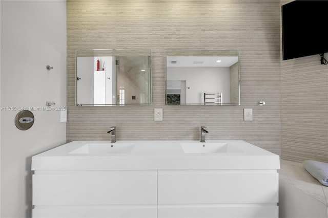 bathroom featuring double vanity, decorative backsplash, tile walls, and a sink