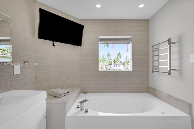 bathroom featuring tile walls, a bath, and vanity