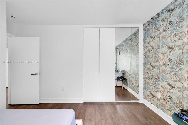 bedroom with a closet, baseboards, and wood finished floors