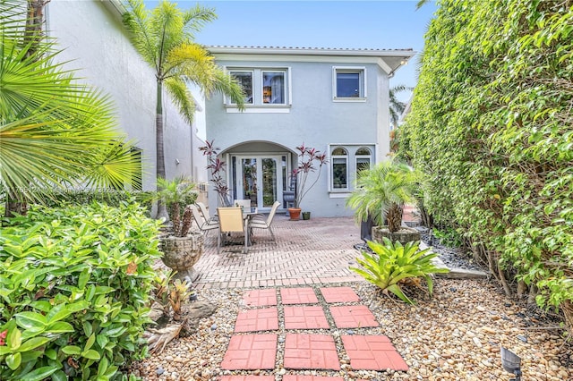 rear view of house featuring stucco siding, french doors, and a patio