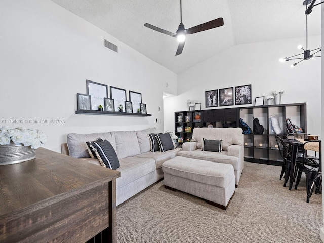 carpeted living area featuring ceiling fan with notable chandelier, visible vents, and high vaulted ceiling