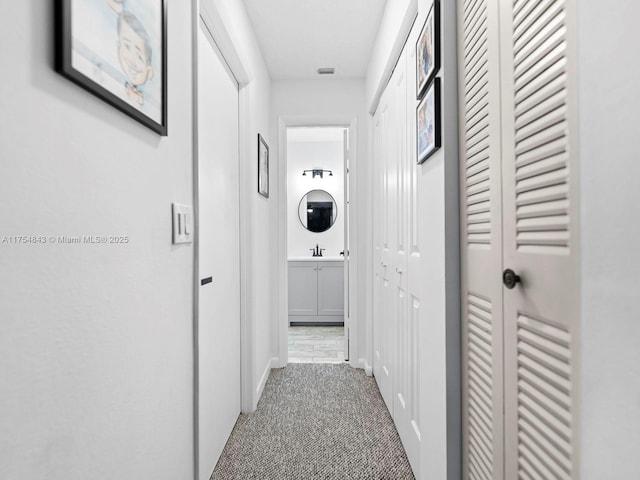 hallway featuring carpet floors and a sink