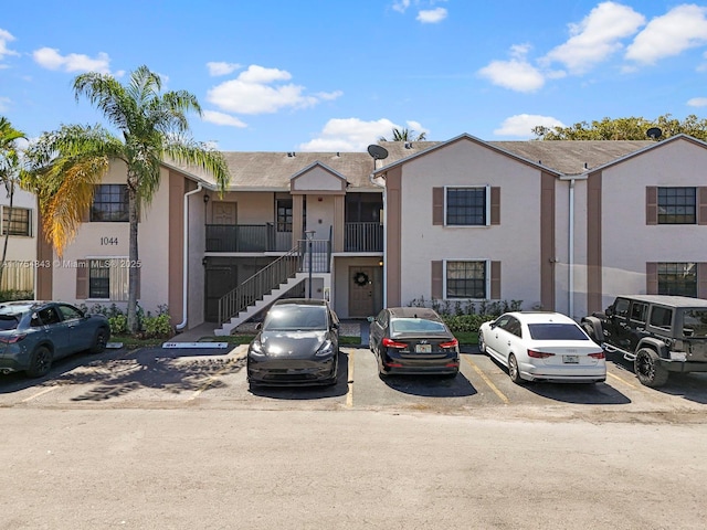 multi unit property with stairs, uncovered parking, and stucco siding