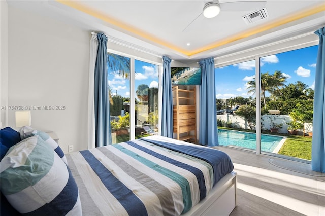 bedroom featuring access to exterior, wood finished floors, and a raised ceiling