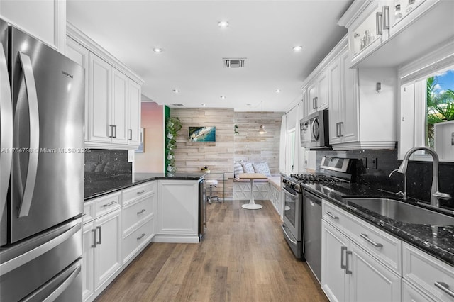 kitchen with appliances with stainless steel finishes, a sink, white cabinets, recessed lighting, and backsplash