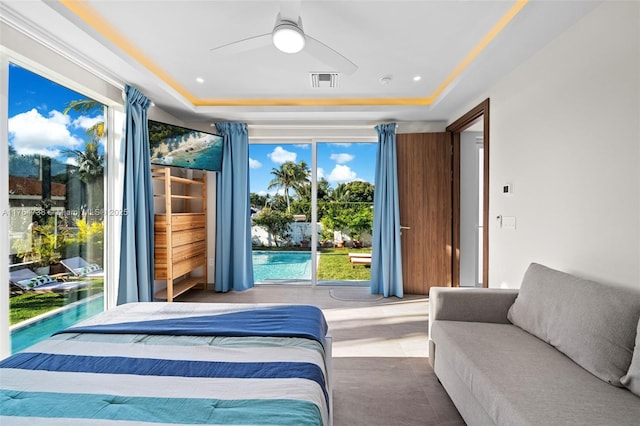 bedroom with a raised ceiling, access to exterior, and a ceiling fan