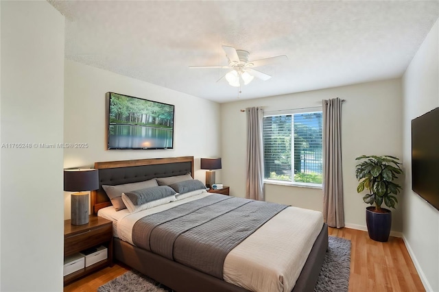 bedroom with a ceiling fan, light wood-type flooring, and baseboards