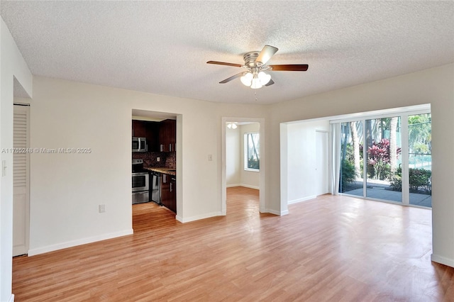 spare room featuring light wood-type flooring, baseboards, a textured ceiling, and a ceiling fan