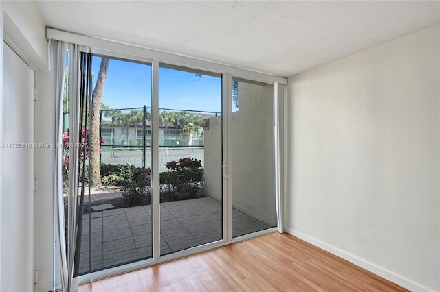 spare room featuring baseboards, wood finished floors, and floor to ceiling windows