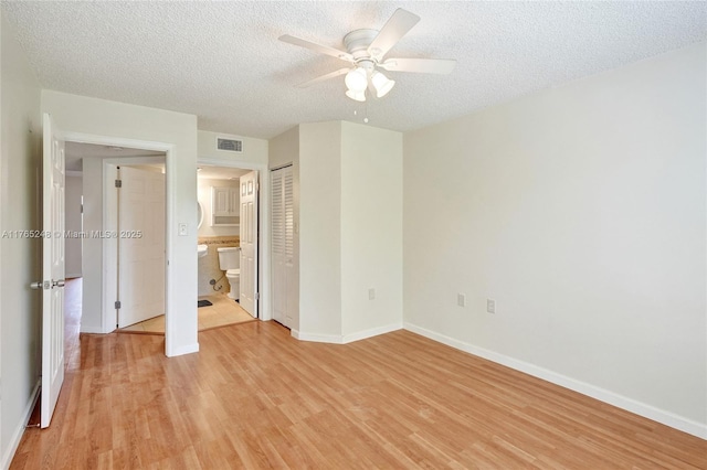 unfurnished bedroom featuring visible vents, baseboards, a textured ceiling, and light wood-style flooring