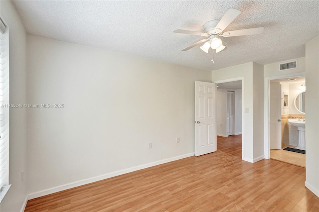 unfurnished bedroom with visible vents, light wood-style floors, and a textured ceiling