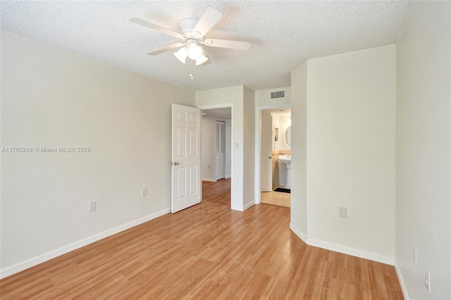 spare room with visible vents, baseboards, light wood-style floors, a textured ceiling, and a ceiling fan