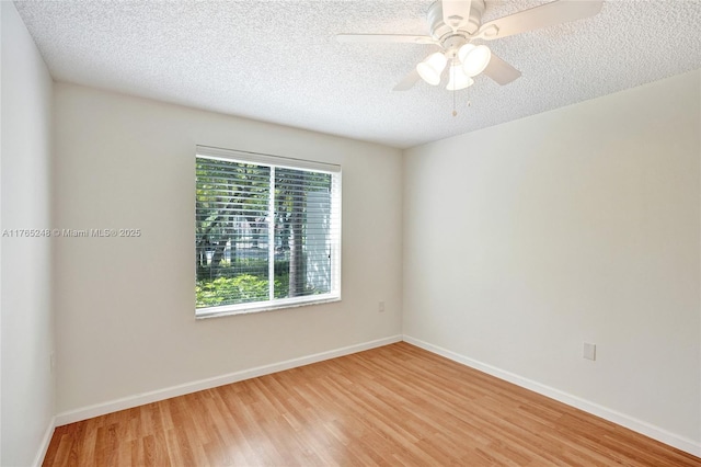 spare room featuring a textured ceiling, baseboards, light wood-style floors, and a ceiling fan