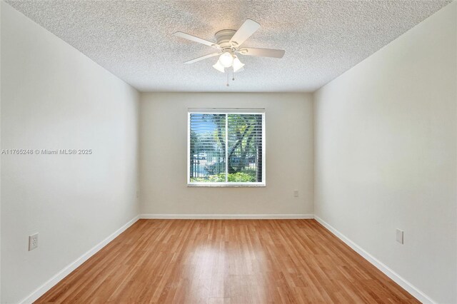 empty room featuring light wood-style flooring, a textured ceiling, baseboards, and a ceiling fan