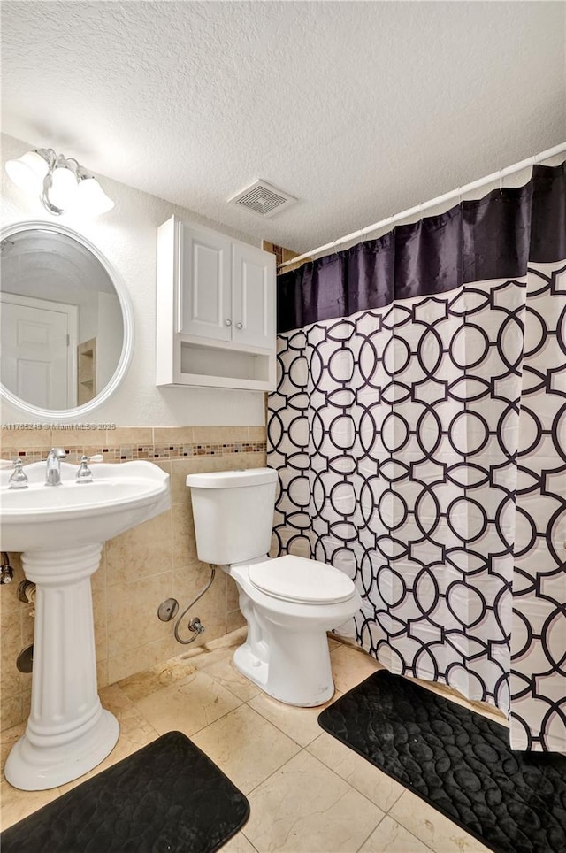 full bathroom with visible vents, tile patterned flooring, a textured ceiling, tile walls, and toilet