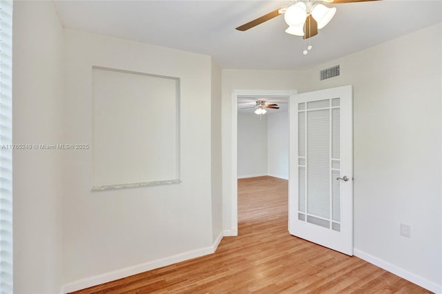 spare room featuring visible vents, baseboards, ceiling fan, and wood finished floors