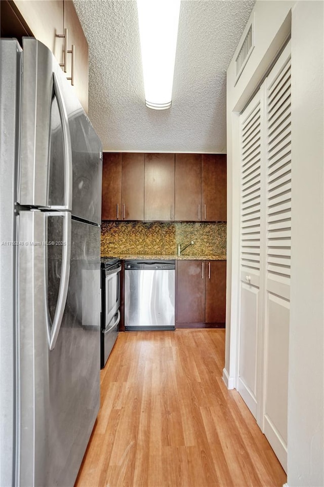 kitchen with visible vents, dark brown cabinetry, stainless steel appliances, light wood-style floors, and a textured ceiling