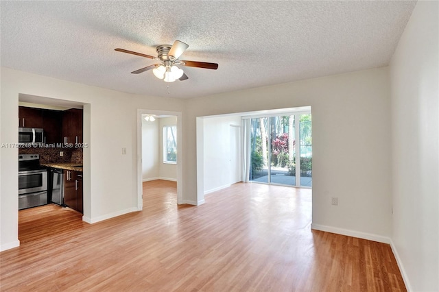 empty room featuring a textured ceiling, baseboards, light wood-style floors, and a ceiling fan