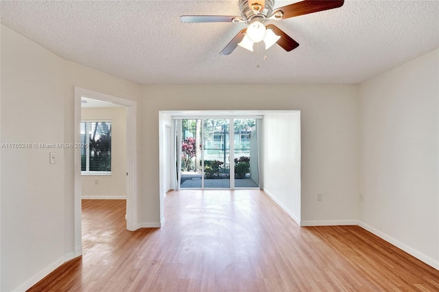 spare room with baseboards, plenty of natural light, light wood-style floors, and a ceiling fan