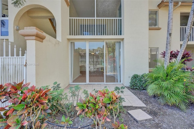 entrance to property with fence and stucco siding