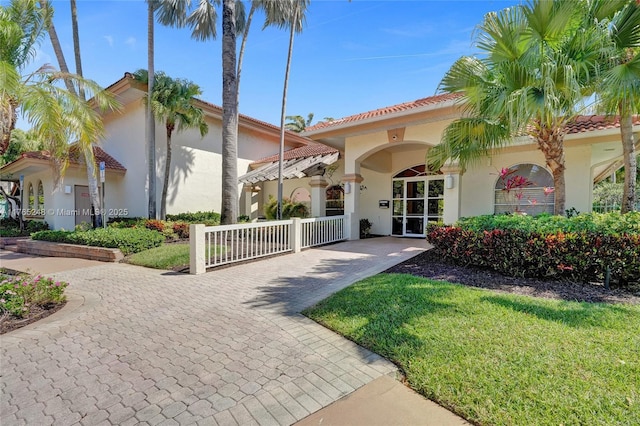 mediterranean / spanish-style house featuring stucco siding, a front yard, and a tiled roof