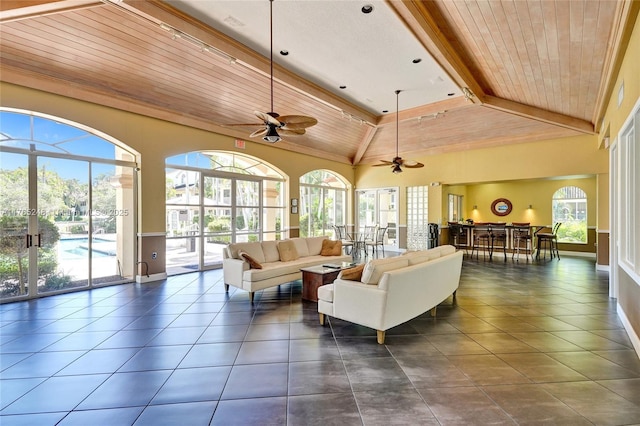 living area featuring beam ceiling, high vaulted ceiling, dark tile patterned floors, wooden ceiling, and ceiling fan